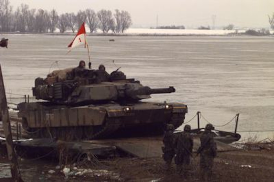 U.S. Army soldiers watch as a M-1 Abrams Main Battle Tank from the 1st Armored Division crosses the U.S. Army pontoon bridge over the Sava River from Zupania, Croatia, into Bosnia and Herzegovina on Dec. 31, 1995. The bridge has become one of the primary routes for the NATO Implementation Force (IFOR) deployment into Bosnia and Herzegovina for Operation Joint Endeavor. 