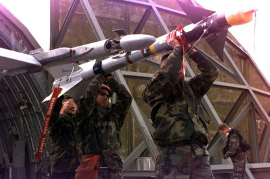U.S. Marine Sgt. Rene R. Benedit (left), Lance Cpl. Ricardo Almaguer (center) and Lance Cpl. Keith Holmes (right), carry a AIM-9 Sidewinder missile to its station on a Marine F/A-18 Hornet at Aviano Air Base, Italy, as it is prepared for a mission over Bosnia and Herzegovina on Dec. 28, 1995. The Hornet's mission is in support of the NATO Implementation Force (IFOR) in Operation Joint Endeavor. The Marines and their aircraft are deployed to Aviano from Fighter Attack (All Weather) Squadron 224 of Beaufort, S.C. 