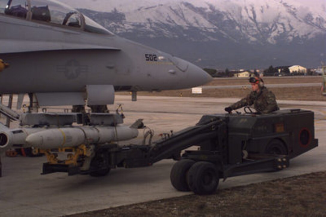 U.S. Marine Cpl. John L Watts drives a weapons loader as he transports weapons to a F/A-18 Hornet for loading at Aviano Air Base, Italy, as the aircraft is prepared for a mission over Bosnia and Herzegovina on Dec. 28, 1995. The Hornet's mission is in support of the NATO Implementation Force (IFOR) in Operation Joint Endeavor. The Marines and their aircraft are deployed to Aviano from Fighter Attack (All Weather) Squadron 224 of Beaufort, S.C. 