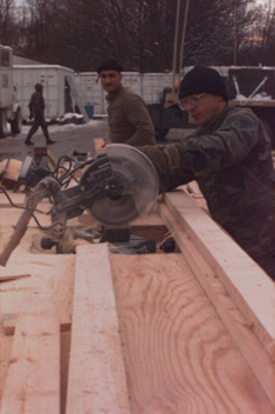 U.S. Air Force Red Horse engineers saw lumber for tent frames as they build a tent city at Tuzla Air Base, Bosnia and Herzegovina, on Dec. 31, 1995. The wood is being cut to size to form the ridges on the ceiling support for the hard backed tents. The tents will be used to house U.S. Army and Air Force troops at Tuzla Air Base. The engineers are from the 823rd Red Horse Civil Engineering Squadron, Hurlburt Field, Fla. 