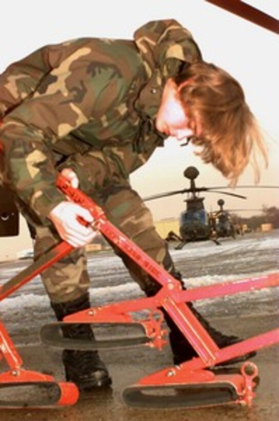 A U.S. Army helicopter mechanic sets up a helicopter blade stowage bracket for a OH-58D Kiowa Warrior helicopter at Rhein Main Air Base, Germany, on Jan. 3, 1996. The OH-58's will be loaded into Air Force cargo aircraft and deployed to bases in Bosnia and Herzegovina as part of the NATO Implementation Force (IFOR). The Kiowa is a two seat, single engine, four-bladed main rotor, scout helicopter with a low light television, thermal imaging system and a laser rangefinder/designator incorporated into a mast mounted sight. The mechanic and the helicopters are from the 3rd Battalion of the 4th Aviation Brigade Cavalry Unit, Schweifurt, Germany. 