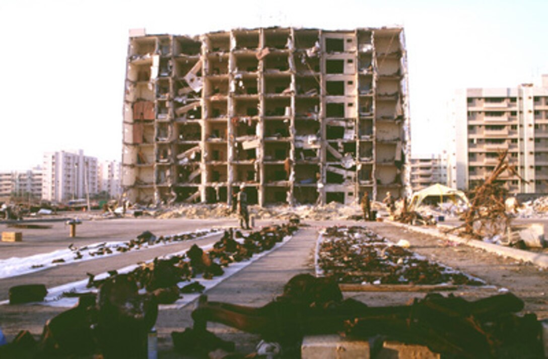 U.S. and Saudi law enforcement and military personnel lay parts of vehicles and debris on plastic sheets as they gather evidence and search for clues on June 29, 1996, leading to the identity of the terrorists who set off the explosion of a fuel truck outside the northern fence of the Khobar Towers complex near King Abdul Aziz Air Base, Dhahran, Saudi Arabia. The explosion at 2:55 p.m. EDT, Tuesday, June 25, 1996, killed 19 and injured over 260. The building housed U.S. military personnel and served as the headquarters for the U.S. Air Force's 4404th Wing (Provisional), Southwest Asia. 