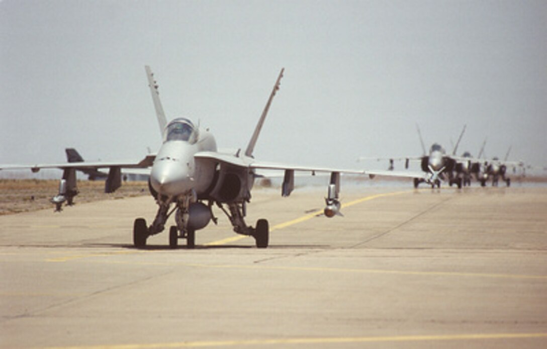 A U.S. Navy F/A-18 Hornet leads other Hornets as they taxi towards the de-armament area set up at the Roswell, N.M., airport on June 9, 1996. The fighter/attack jets are conducting bombing missions for the Red Forces during exercise Roving Sands '96. Roving Sands '96 is the world's largest joint, tactical air defense exercise involving service men and women from the U.S., Germany, the Netherlands and Canada. The exercise allows multinational forces to practice tactics, techniques and procedures improving their defense capabilities. The Hornets are deployed for the exercise from Strike Fighter Squadron 151, Naval Air Station Lemoore, Calif. 