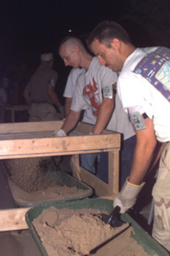 U.S. Air Force personnel help sift through sand and dirt outside Khobar Towers, Saudi Arabia, on July 1, 1996, for clues that could help the FBI in their investigation of the June 25th bombing. The explosion of a fuel truck, set off by terrorists outside the northern fence of the Khobar Towers complex near King Abdul Aziz Air Base, killed 19 and injured over 260. The facility housed U.S. service members and served as the headquarters for the 4404th Wing. U.S. and Saudi law enforcement and military personnel are combing through the blast area searching for clues to the identity of the terrorists. 