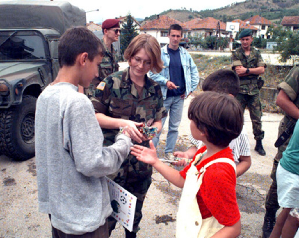 Staff Sgt. Faith Morris, of the 360th Civil Affairs Brigade, passes out crayons and coloring books to school children in Visegrad, Bosnia and Herzegovina, during Operation Joint Endeavor on July 16, 1996. The U.S. Army soldier is deployed as part of the NATO Implementation Force (IFOR) in Bosnia and Herzegovina from Fort Jackson, S.C. 