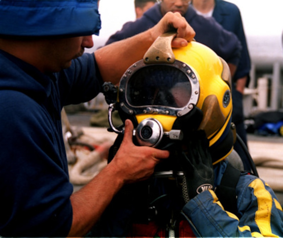 U.S. Navy Diver Petty Officer 2nd Class Brad Fleming is assisted with his Mark-21 diving helmet in preparation for his next dive during search and recovery operations at the TWA Flight 800 crash site offshore of Moriches Inlet, Long Island, N.Y., on July 25, 1996. Fleming, a Palatka, Fla. native is a Navy Hull Technician. 