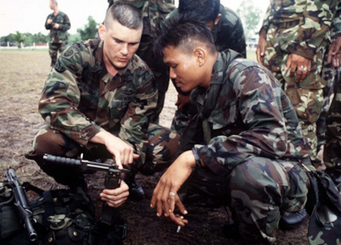 U.S. Army Sgt. 1st Class Lauren Burnham (left) explains to a Royal Thai Army soldier a wire cutting technique using an M-9 bayonet during the cross training portion of Exercise Cobra Gold '96 at Nakhon Si Thammarat, Thailand, on May 1, 1996. Cobra Gold '96 is the latest in a continuing series of U.S. /Thai military exercises designed to ensure regional peace and strengthen the ability of the Royal Thai Armed Forces to defend Thailand. Approximately 9,000 U.S. and 10,000 Thai personnel are participating in the exercise. Burnham is attached to Alpha Company, 2nd Battalion, 1st Infantry, 6th Infantry Division. 
