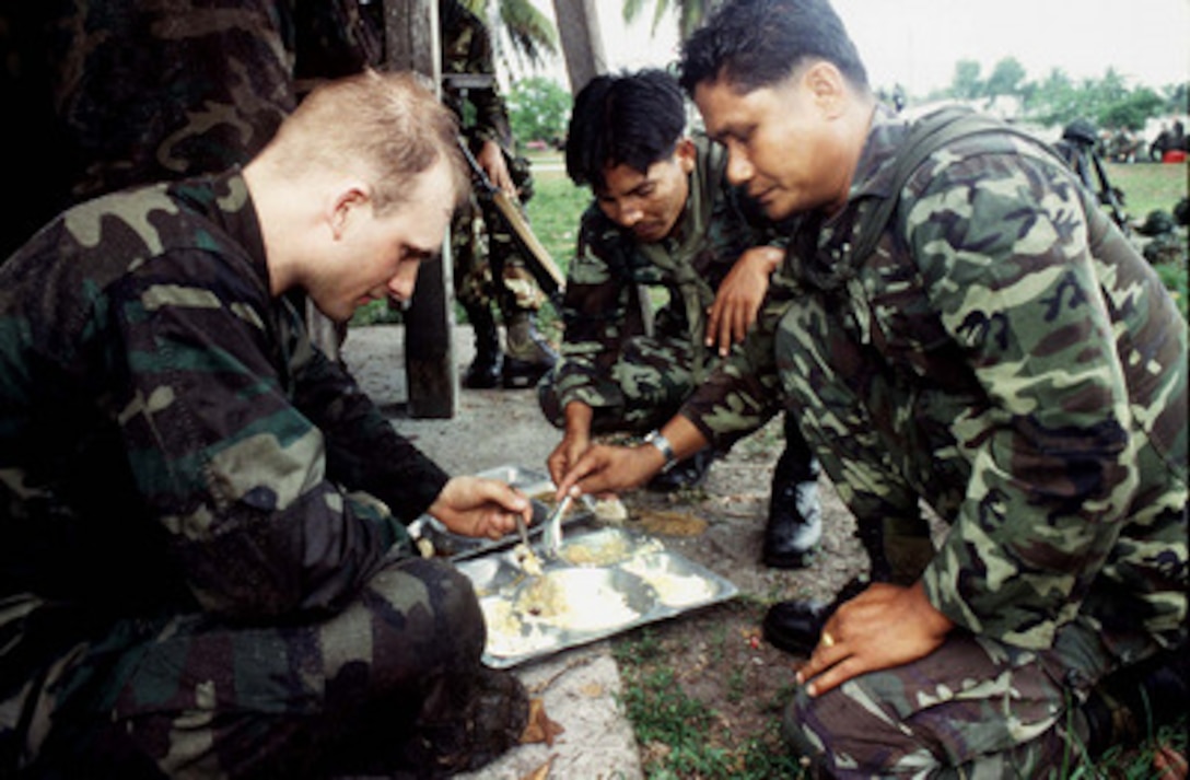 Soldiers from the 5th Long Range Reconnaissance Patrol Company, Royal Thai Army, (right) share their traditional field chow with a member of the U.S. Army's 6th Infantry Division (left) during the cross training portion of Exercise Cobra Gold '96 at Nakhon Si Thammarat, Thailand, on May 1, 1996. Cobra Gold '96 is the latest in a continuing series of U.S. /Thai military exercises designed to ensure regional peace and strengthen the ability of the Royal Thai Armed Forces to defend Thailand. Approximately 9,000 U.S. and 10,000 Thai personnel are participating in the exercise. 