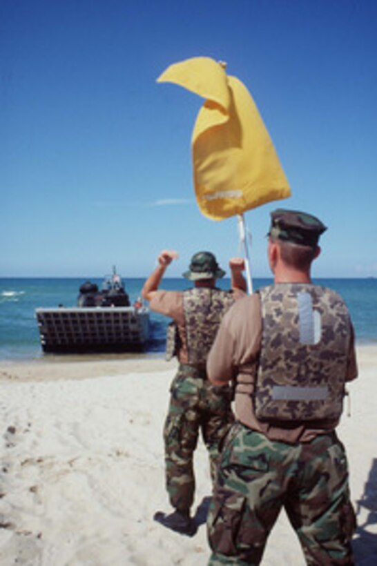 U.S. Navy Beach Masters from Beach Master Unit One direct an arriving landing craft to the landing zone at Narathiwat, Thailand, on May 5, 1996, during a phase of Exercise Cobra Gold '96. Cobra Gold '96 is the latest in a continuing series of U.S. /Thai military exercises designed to ensure regional peace and strengthen the ability of the Royal Thai Armed Forces to defend Thailand. Approximately 9,000 U.S. and 10,000 Thai personnel are participating in the exercise. 