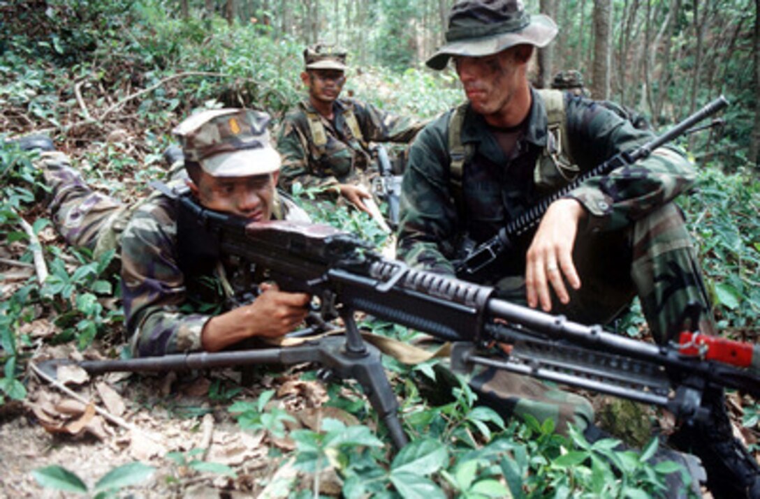 Royal Thai Marine Sgt. Arkom Jaiwijit (left) sights-in on his M-60E3 Machine Gun while U.S. Marine Sgt. Charles Hutto (right) explains the weapon's operation during the cross training portion of Exercise Cobra Gold '96 at Narathiwat, Thailand, on May 6, 1996. Cobra Gold '96 is the latest in a continuing series of U.S. /Thai military exercises designed to ensure regional peace and strengthen the ability of the Royal Thai Armed Forces to defend Thailand. Approximately 9,000 U.S. and 10,000 Thai personnel are participating in the exercise. Jaiwijit is attached to 1st Company, 9th Battalion, 3rd Regiment, Royal Thai Marines. Hutto is attached to Alpha Company, 1st Battalion, 7th Marines. 