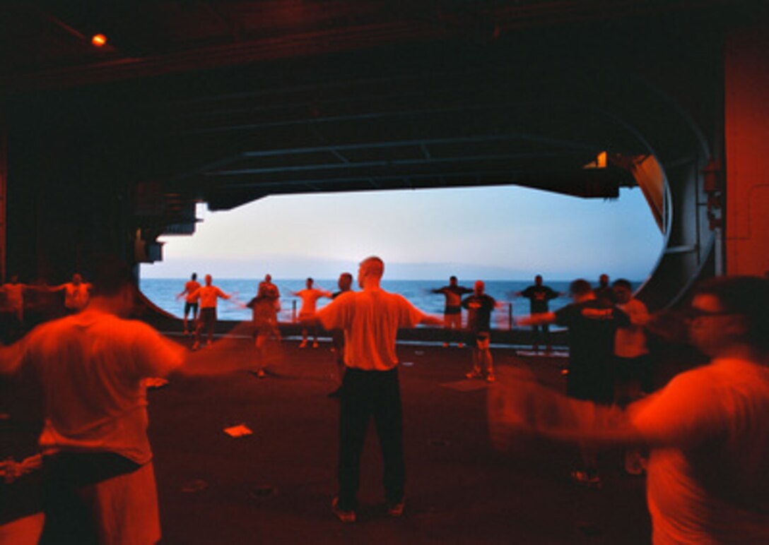 As the sun sets in the North Arabian Sea on May 9, 1996, crew members onboard the aircraft carrier USS George Washington (CVN 73) participate in physical readiness training under the red lights of Hangar Bay Two. The red lights help to preserve the night vision of the crew members. The George Washington and its battle group were operating in the Arabian Gulf where they conducted air patrols in support of Operation Southern Watch. Southern Watch is the U.S. and coalition enforcement of the no-fly-zone over Southern Iraq. 