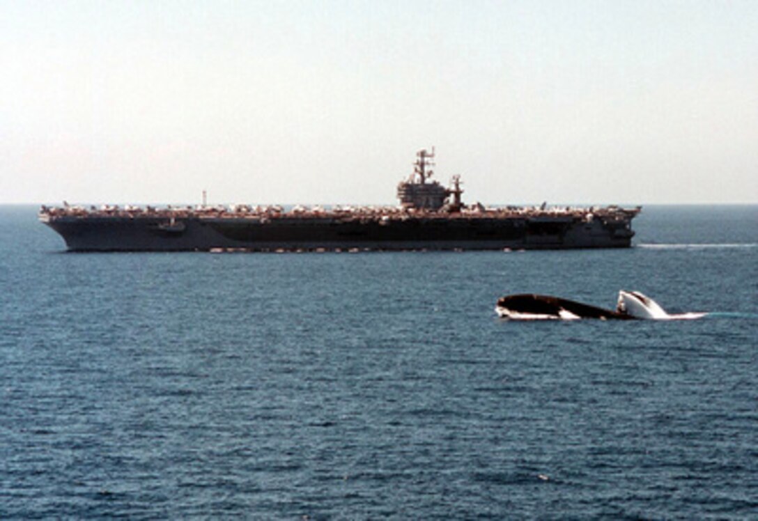 The Los Angeles-class attack submarine USS Scranton (SSN 756) surfaces in the North Arabian Sea while the aircraft carrier USS George Washington (CVN 73) cruises in the background on May 9, 1996. The George Washington and its battle group were operating in the Arabian Gulf where they conducted air patrols in support of Operation Southern Watch. Southern Watch is the U.S. and coalition enforcement of the no-fly-zone over Southern Iraq. 