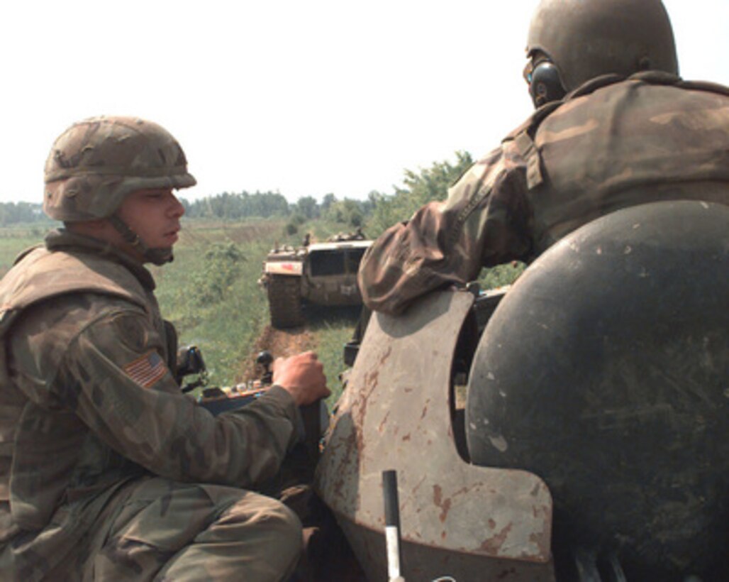 Sgt. Felix Gonzales uses a control box to remotely control a Panther armored mine clearing vehicle in front of the M-113 Armored Personnel Carrier he is riding on during Operation Joint Endeavor on May 16, 1996, in Bosnia and Herzegovina. The remotely controlled Panther, based on a modified M-60 tank hull, is being used to ensure the road near McGovern Base is clear of mines. Gonzales is attached to the 23rd Engineer Battalion, 1st Brigade, 1st Armored Division. 