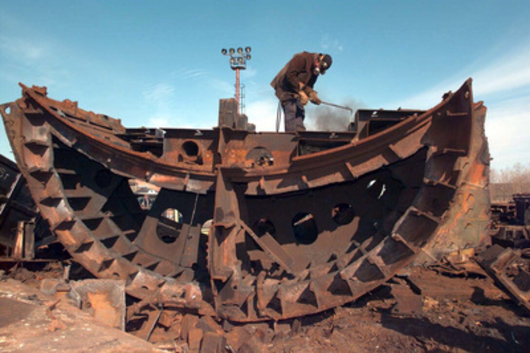 A Russian shipyard worker uses a cutting torch to breakdown a large bulge section of a Russian Oscar Class submarine at the Little Star shipyard in Severodvinsk, Russia, May 29, 1996. Russian ballistic submarines are being dismantled as part of the Nunn-Lugar/Cooperative Threat Reduction Program. 