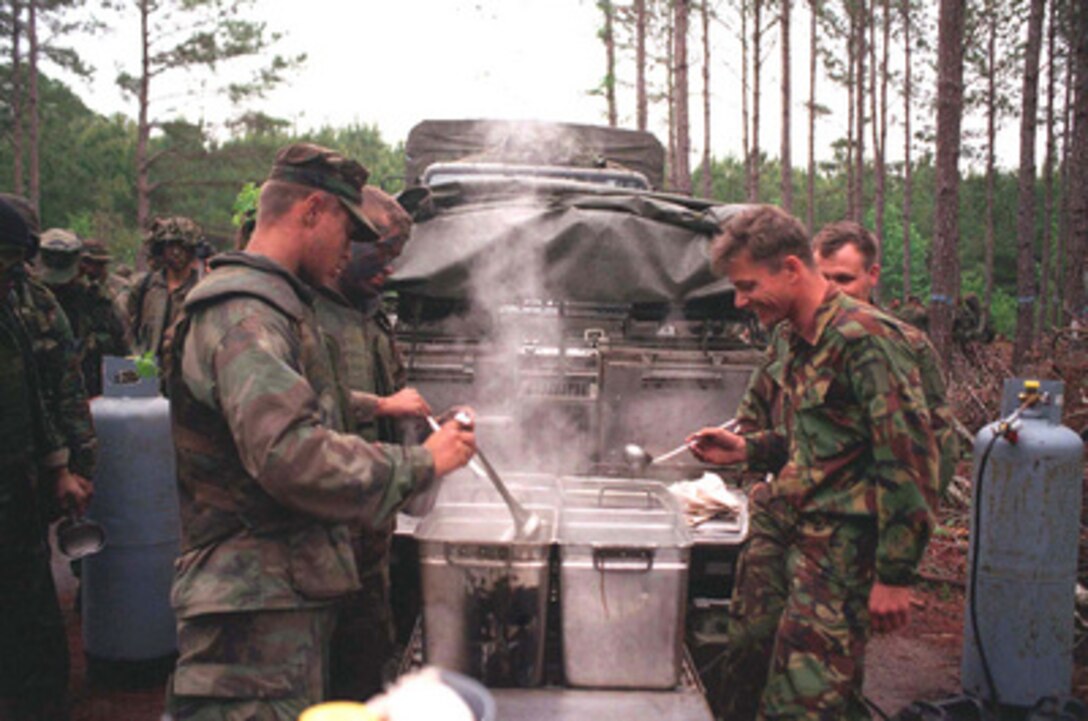 British Royal Marines (right) from 42 Commando offer hot water to make coffee and tea to U.S. Marines from Kilo Company as they break for chow at Camp Lejeune, N.C., during Combined Joint Task Force Exercise '96 on May 16, 1996. More than 53,000 military service members from the United States and the United Kingdom are participating in Combined Joint Task Force Exercise '96 on military installations in the Southeastern United States and in waters along the Eastern seaboard. 