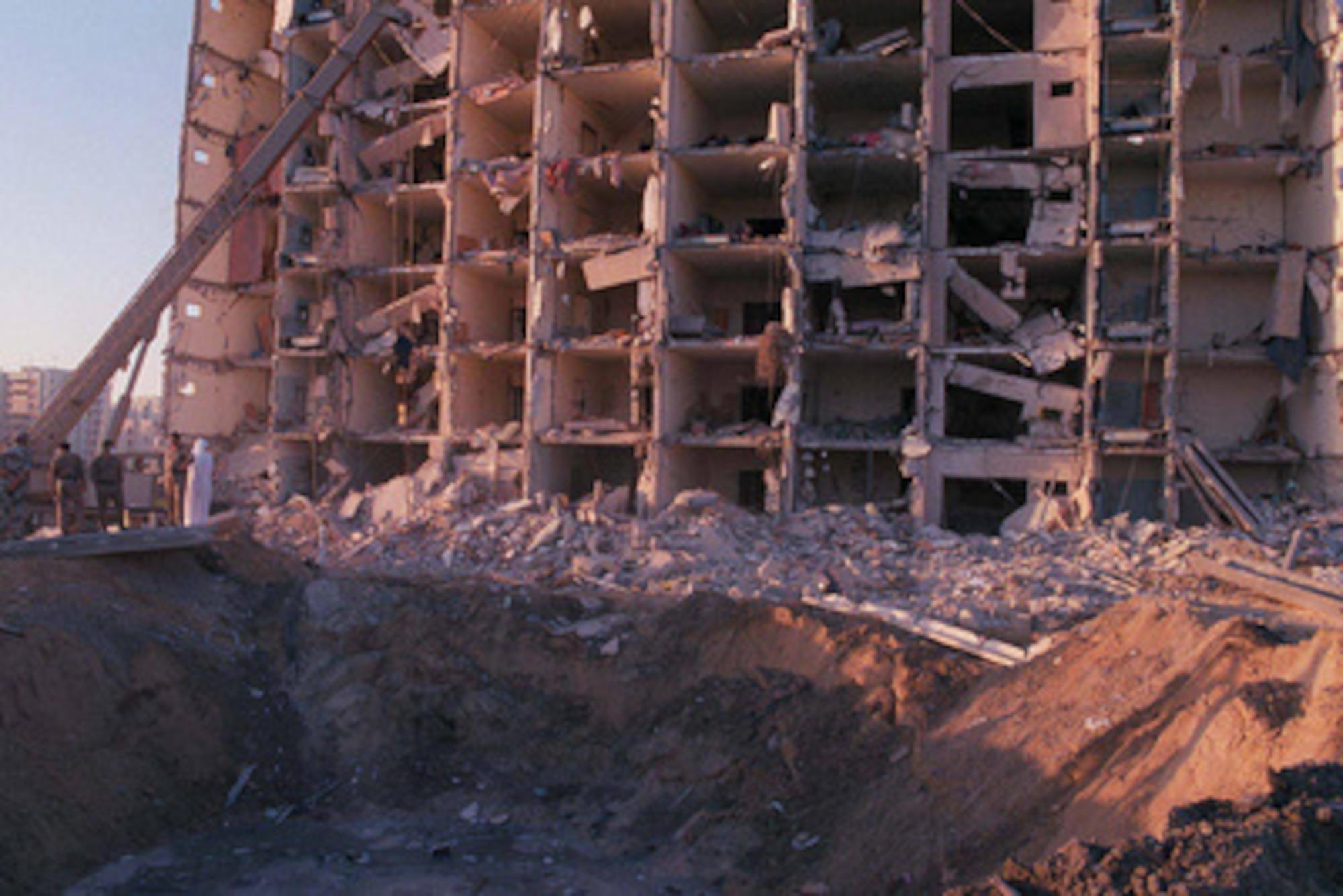 U.S. and Saudi military personnel survey the damage to Khobar Towers caused by the explosion of a fuel truck outside the northern fence of the facility on King Abdul Aziz Air Base near Dhahran, Saudi Arabia, at 2:55 p.m. EDT, Tuesday, June 25, 1996. Several buildings were damaged and there were numerous U.S. casualties. The latest information from Dhahran indicates that 19 people are dead and 64 people are hospitalized. Additionally, over 200 have been treated for injuries and released. The facility houses U.S. service members and serves as the headquarters for the U.S. Air Force's 4404th Wing (Provisional), Southwest Asia.