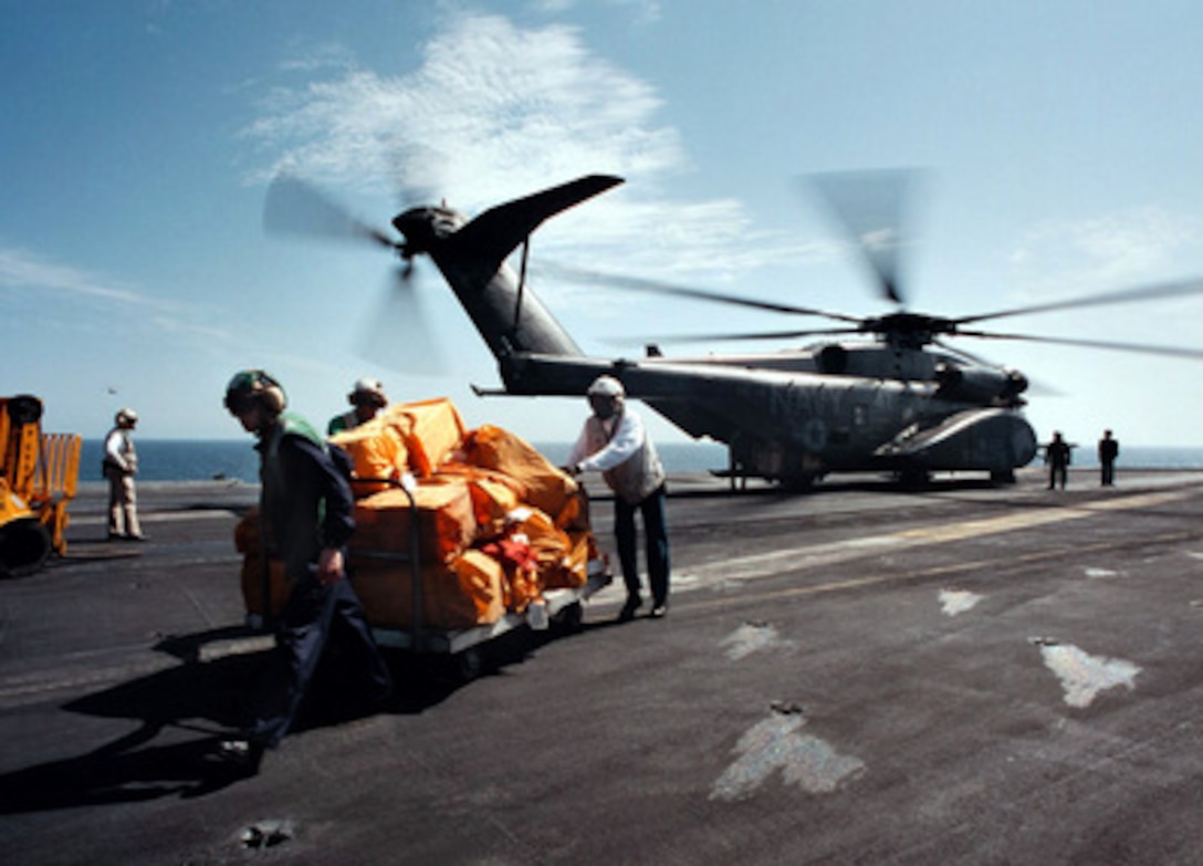 Sailors unload mail from a CH-53E (Super Stallion) from the combat stores ship USNS Sirius (TAFS 8) on the flight deck of aircraft carrier USS George Washington (CVN 73) on April 5, 1996. The George Washington is currently deployed to the Arabian Gulf in support of Operation Southern Watch. 