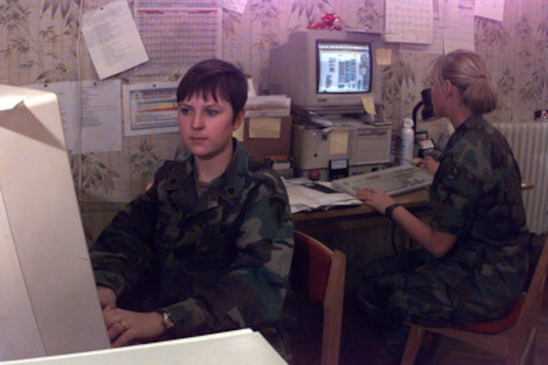 Specialist Amanda Griffin (left), from the reserve 221st Public Affairs Detachment out of Schwetzingen, Germany, types a story on her desktop computer. Specialist Griffin is the editor of the newspaper American Endeavor in Taszar, Hungary, published in support of Operation Joint Endeavor. 