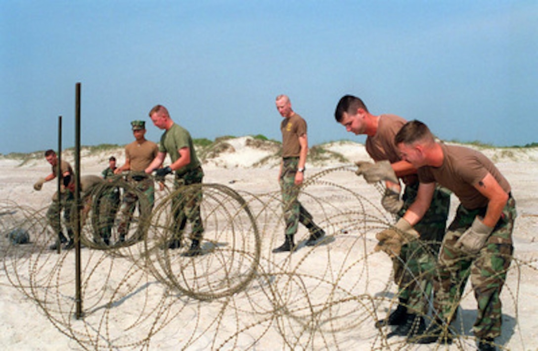 U.S. Marines from Bravo Company, 2nd Combat Engineer Battalion, unroll concertina wire on Onslow Beach, Camp Lejeune, N.C., on May 6, 1996, as they prepare for Combined Joint Task Exercise 96. The wire will serve as an obstacle on D-day of the exercise. More than 53,000 military service members from the United States and the United Kingdom are participating in Combined Joint Task Force Exercise 96 on military installations in the Southeastern United States and in waters along the Eastern seaboard. 