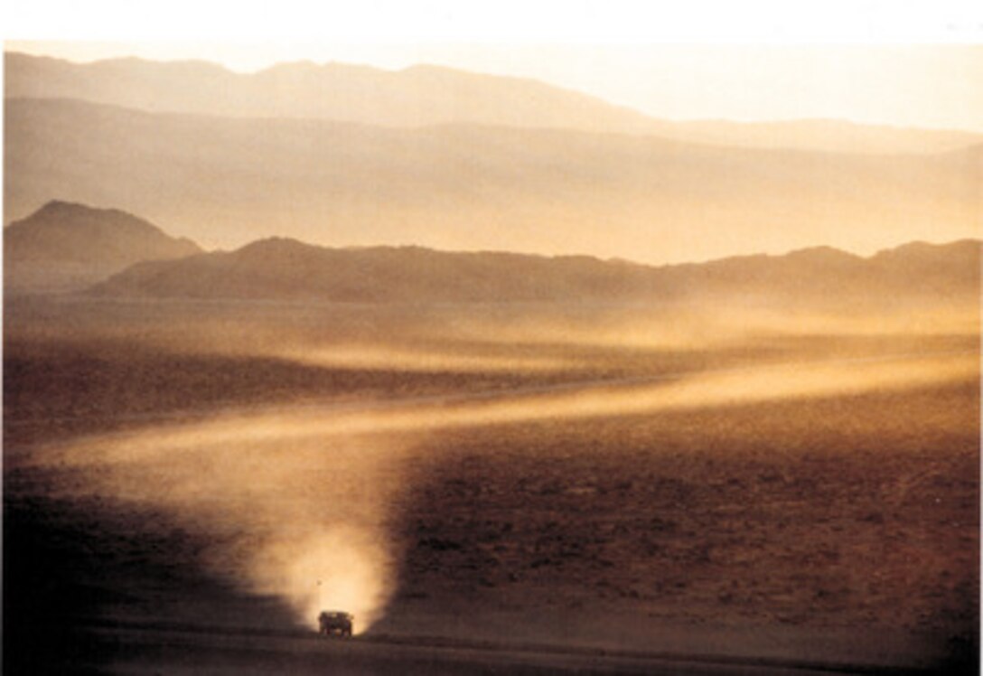 Second Place Pictorial  'Alone in the Desert' by Tech. Sgt. Scott Stewart, U.S. Air Force.  A U.S. Air Force Forward Air Controller drives his jeep across the barren tank and artillery range battlefield at Fort Irwin, Calif. His is searching for a location to call in awaiting Air Force fighter aircraft, which will attack various tanks and artillery who are simulating an enemy threat.