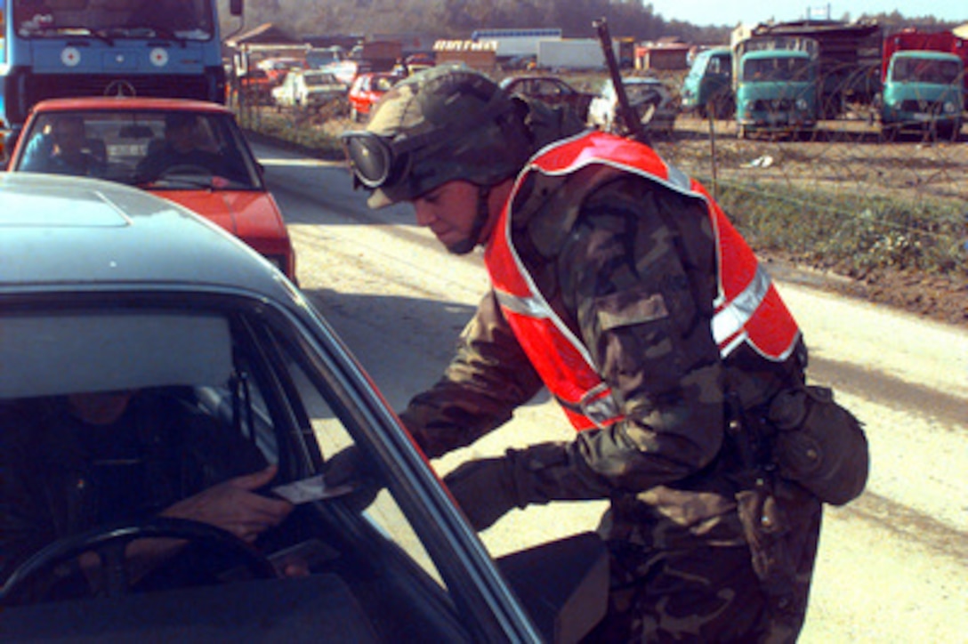 U.S. Army Pfc. Brent Adams checks a driver's identification card during a stop at checkpoint 2A along Route Arizona in Bosnia and Herzegovina on Oct. 27, 1996. Adams is deployed to Bosnia and Herzegovina for Operation Joint Endeavor with A Company 1-77th Armor, 1st Infantry Division. 