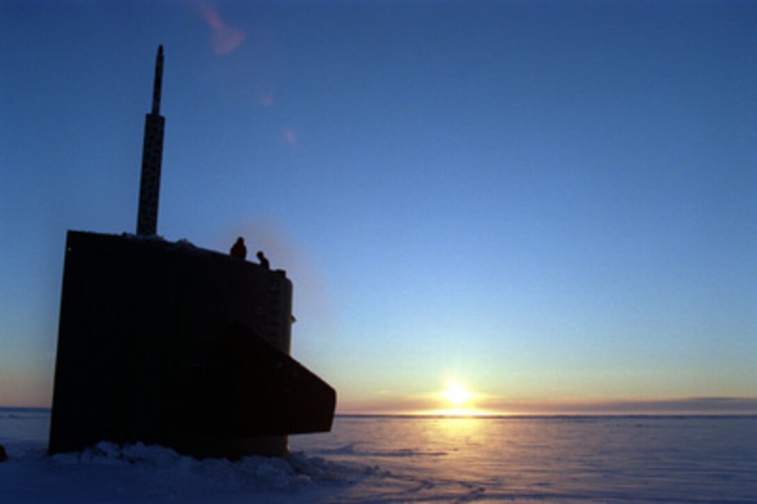 Two crew members of the attack submarine USS Pogy (SSN 647) survey the ice surrounding them after the sub surfaced at sunrise through a 6 inch thick layer of Arctic ice flow. The submarine is on a 45-day research mission to the North Pole. Seven scientists and technical advisors are conducting experiments and collecting samples for studies in water mass properties, geophysics, ice mechanics and pollution detection in the Arctic Ocean. The research voyage is the second of five planned deployments through the year 2000. 