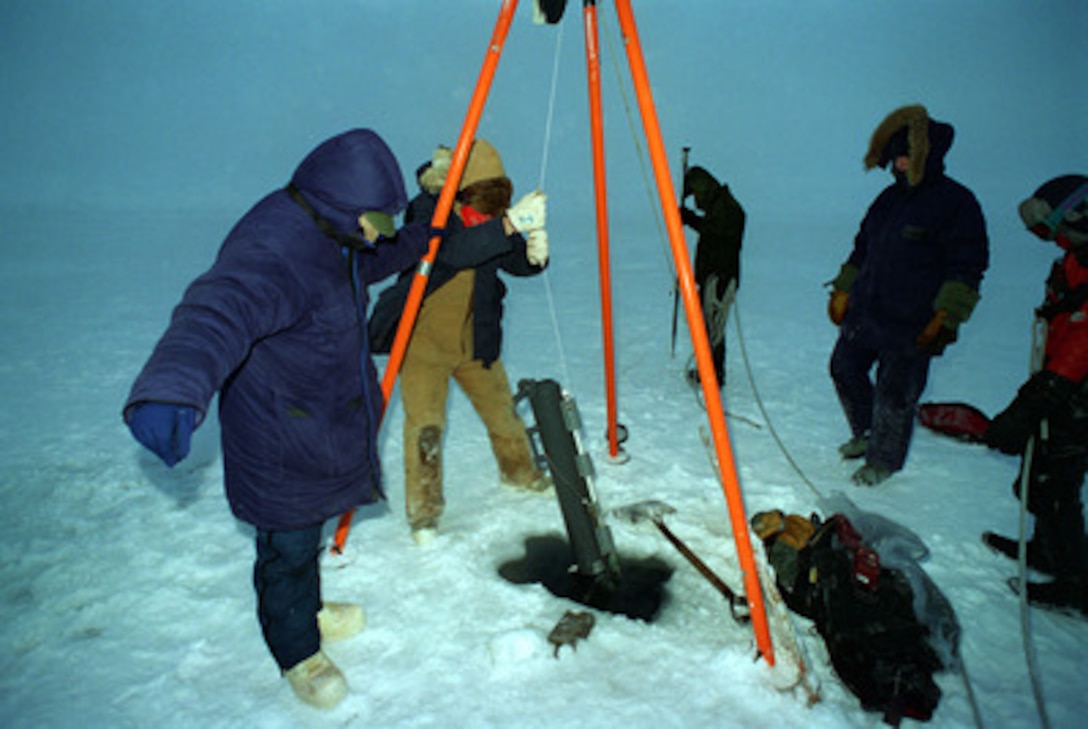 Scientists embarked on board the attack submarine USS Pogy (SSN 647) lower a Nisken Bottle through a hole in the Arctic ice to collect deep water samples. The submarine is on a 45-day research mission to the North Pole. Seven scientists and technical advisors are conducting experiments and collecting samples for studies in water mass properties, geophysics, ice mechanics and pollution detection in the Arctic Ocean. The research voyage is the second of five planned deployments through the year 2000. 