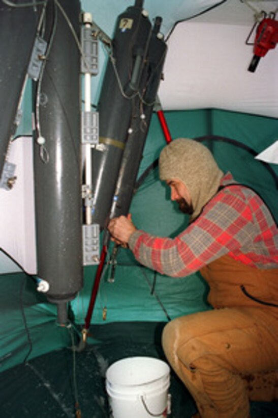 Columbia University scientist Jay Ardie works to decant deep water samples from Nisken bottles hanging in a temporary enclosure on the deck of the attack submarine USS Pogy (SSN 647). The submarine is on a 45-day research mission to the North Pole. Seven scientists and technical advisors are conducting experiments and collecting samples for studies in water mass properties, geophysics, ice mechanics and pollution detection in the Arctic Ocean. The research voyage is the second of five planned deployments through the year 2000. 