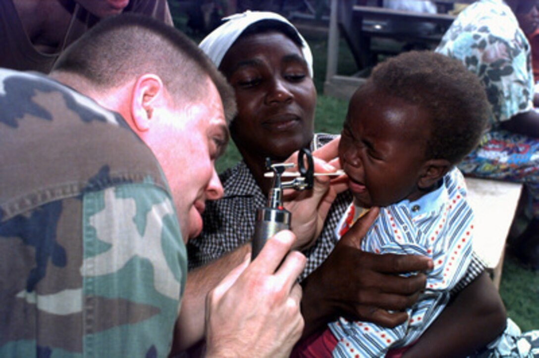 U.S. Army Dr. Victor Worth tries to peer into the mouth of a young Haitian boy during a Exercise Fairwinds humanitarian relief operation in Port-au-Prince, Haiti, on Sept. 5, 1996. Medics from the Fourth Medical Battalion are conducting the relief operation at the RENMEN Foundation (Fondation Pour la Recuperation des Enfants) in Port-au-Prince as part of their medical readiness training. Worth is deployed for the exercise from the Womack Medical Center, Fort Bragg, N.C. 