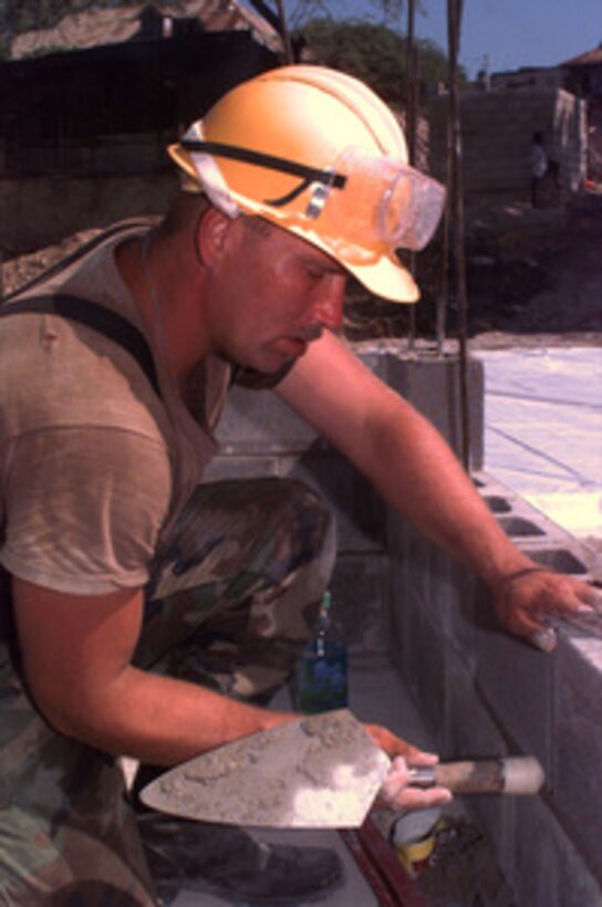 Spc. Kenneth Anderson taps a concrete block into place with his trowel as he lays a course of block as he helps construct a school building at the Isidore School in Port-au-Prince, Haiti, on Sept. 20, 1996. The U.S. Army engineer is deployed to Haiti from the 1st Platoon, Alpha Company, 864th Engineers, Fort Lewis, Wash., for a Exercise Fairwinds humanitarian relief operation. 