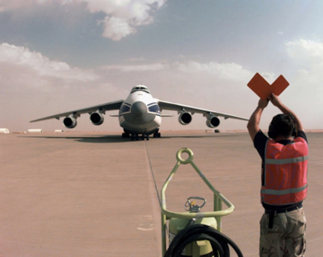 Senior Airman Creig H. Dunlap, of the 615th Air Mobility Maintenance Squadron, marshals an AN-124 Russian transport aircraft to its parking spot on the tarmac at Prince Sultan Air Base, Al Kharj, Saudi Arabia, on Aug. 26, 1996. British personnel are using the charter aircraft to move in equipment to support the Royal Air Force Tornadoes fighter/attack aircraft conducting Operation Southern Watch to Al Kharj. Personnel, aircraft, and equipment are being moved from bases in Dhahran and Riyadh to the remote desert air base to reduce their vulnerability to terrorist attack. Southern Watch is the coalition enforcement of the no-fly-zone over Southern Iraq. Dunlap is deployed from Travis Air Force Base, Calif. 