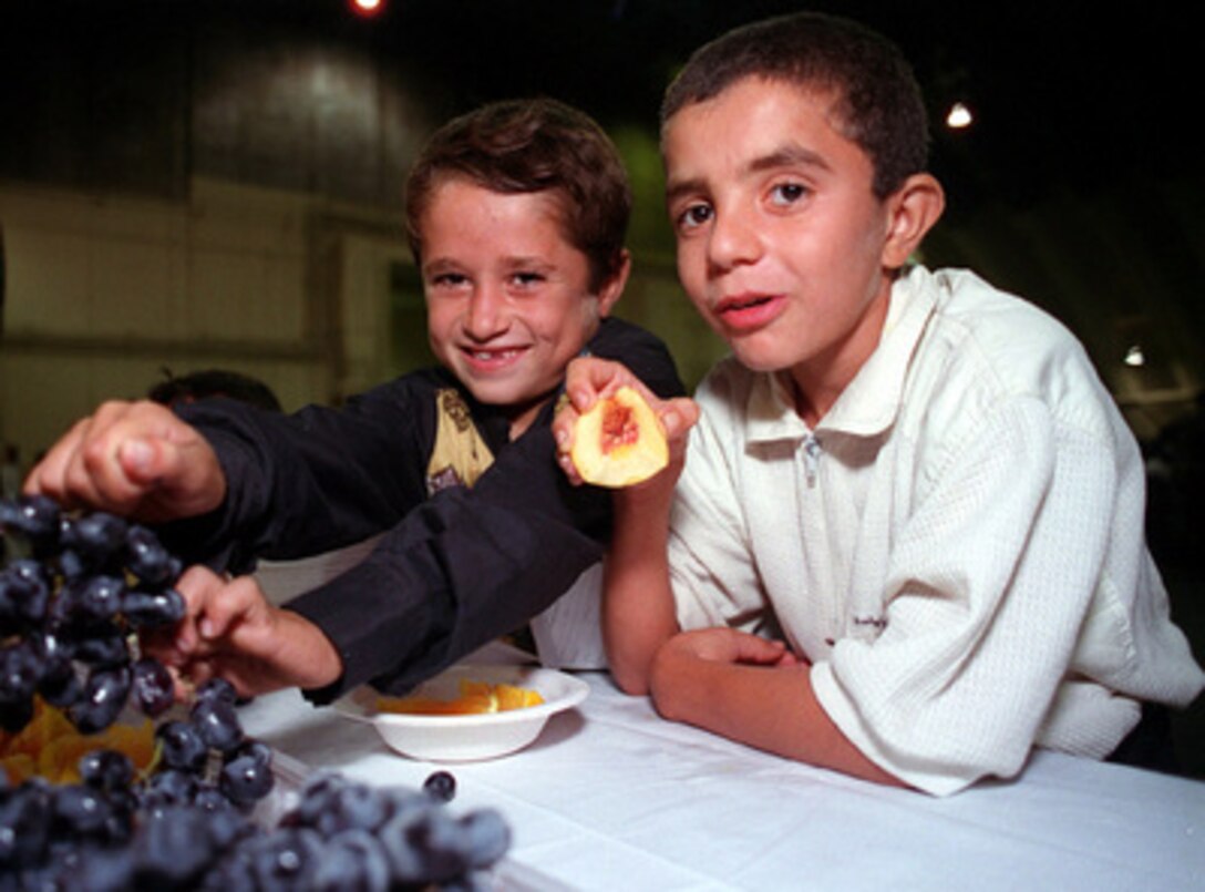 Two young Kurdish evacuees eat fruit at Andersen Air Force Base, Guam, after arriving on a civilian charter flight from Turkey on Sept. 17, 1996, as part of Operation Pacific Haven. These Kurdish evacuees are the first of approximately 2,000 foreign service nationals and their families who were associated with the United States government's humanitarian efforts in Northern Iraq. They will be sheltered and fed at Andersen Air Force Base and processed on a case-by-case basis for entry into the continental United States as quickly as possible. 