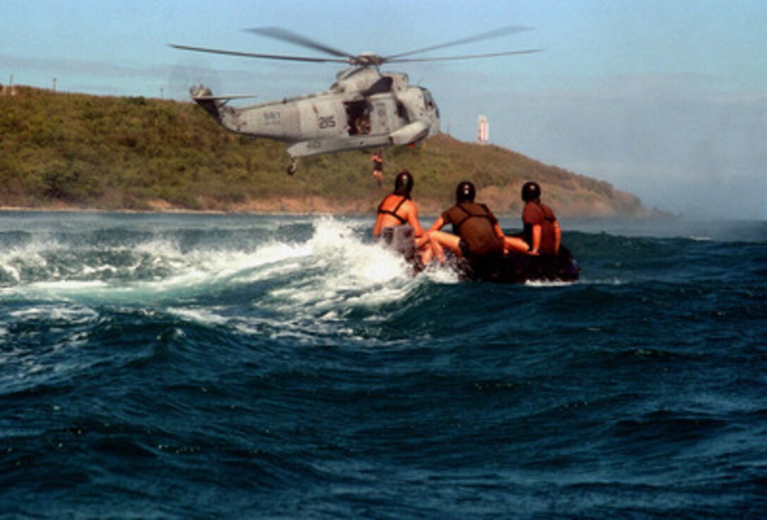 A Explosive Ordnance Disposal technician jumps from a U.S. Navy SH-3H Sea King helicopter into the water as his team mates watch from a combat rubber raiding craft on March 17, 1997. Team members from Explosive Ordnance Disposal Mobil Unit 2 and helicopter crews from Fleet Composite Squadron 8 are practicing insertion and recovery operations off the coast of Naval Station Roosevelt Roads, Puerto Rico. 