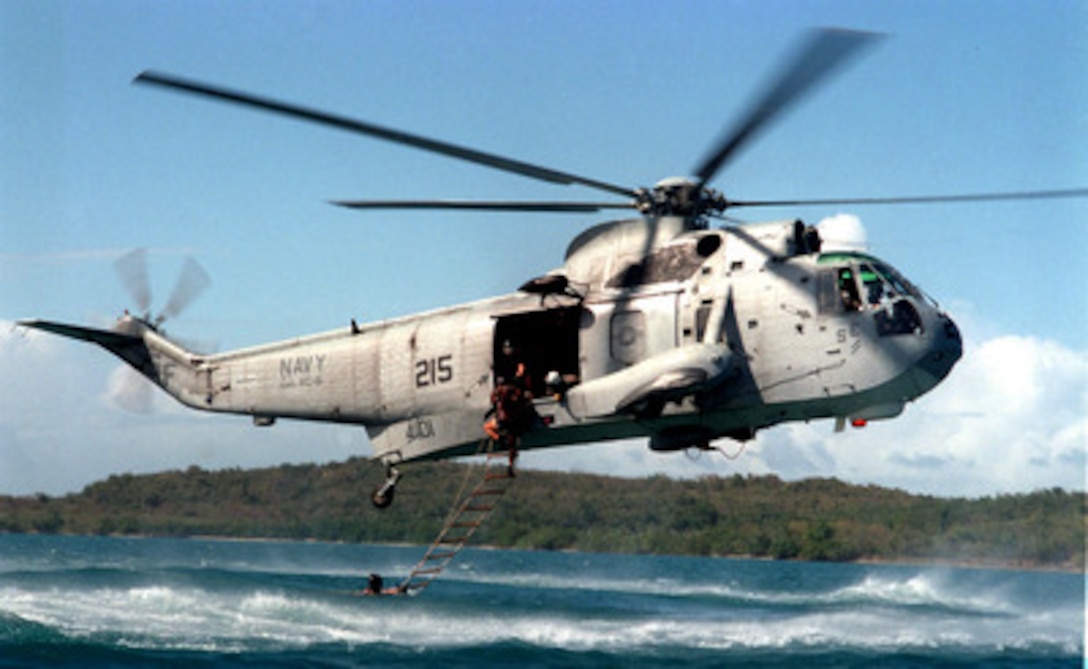 A U.S. Navy SH-3H Sea King helicopter hovers over the water to recover Explosive Ordnance Disposal technicians climbing a ladder to the aircraft on March 17, 1997. Team members from Explosive Ordnance Disposal Mobil Unit 2 and helicopter crews from Fleet Composite Squadron 8 are practicing insertion and recovery operations off the coast of Naval Station Roosevelt Roads, Puerto Rico. 