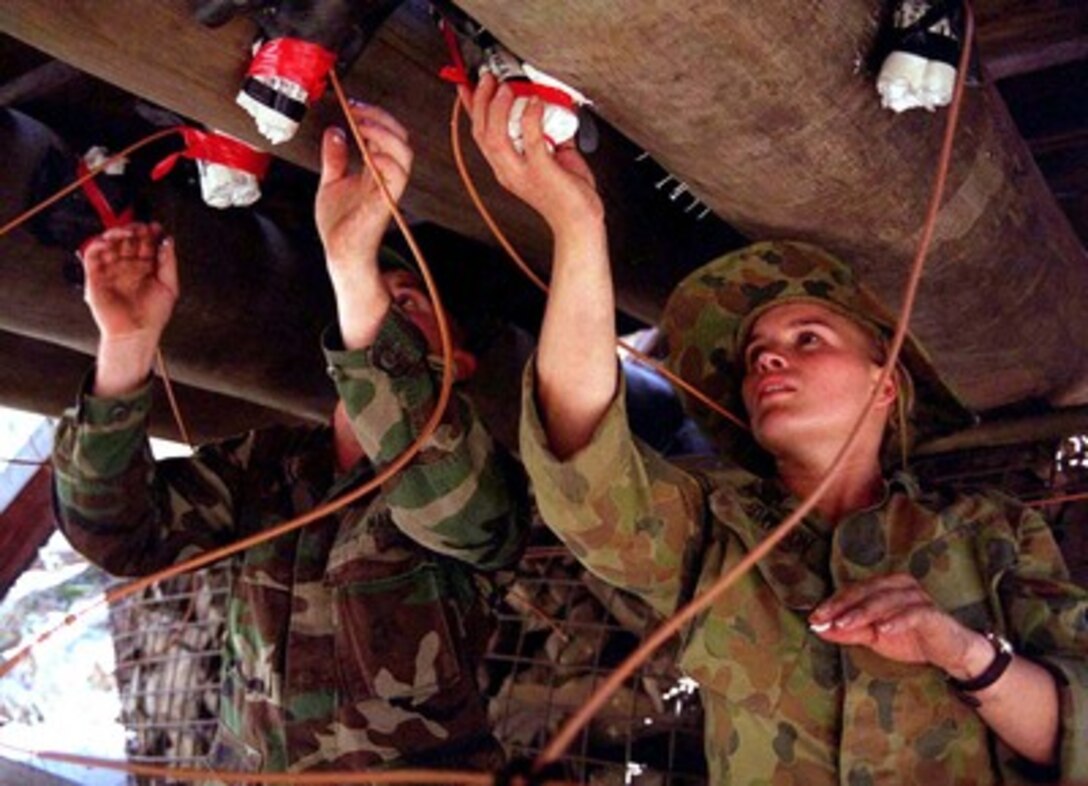 Lance Cpl. Timothy Exley (left) and Sapper Tania Dawson (right) check the placement of explosive charges on a bridge to be demolished in the Shoalwater Training Area, Queensland, Australia, on Feb. 17, 1997, during exercise Tandem Thrust '97. Tandem Thrust is a combined military training exercise involving 28,000 personnel, 252 aircraft and 43 ships, and is designed to train U.S. and Australian staffs in crisis action planning and contingency response operations. Exley is attached to the U.S. Marine Corps 9th Engineering Support Battalion. Dawson is attached to the Australian 21st Construction Squadron. 