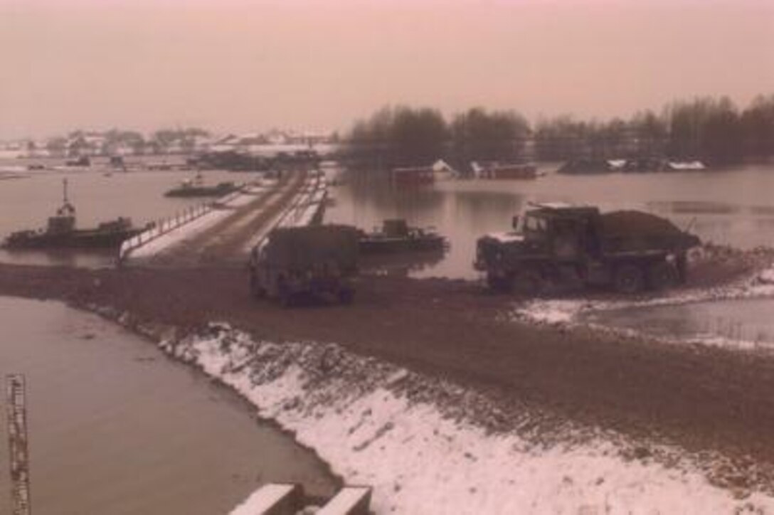 A U.S. Army Humvee heads down the gravel approach road to cross the U.S. Army bridge over the Sava River from Zupania, Croatia, into Bosnia and Herzegovina on Dec. 31, 1995. U.S. Army engineers overcame freezing temperatures, unusual flooding, and other logistical challenges to build the 2,033 foot long bridge, which is longer than the Brooklyn Bridge. The bridge has become one of the primary routes for the NATO Implementation Force (IFOR) deployment into Bosnia and Herzegovina for Operation Joint Endeavor. 