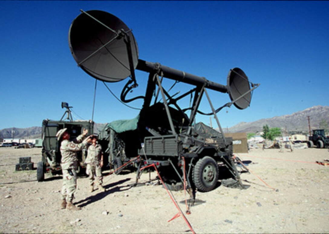 Two members of the 225th Combat Communications Squadron adjust the angle of the dish as they set up a TRAC-170 Wideband System for Exercise Roving Sands 97 at El Paso, Texas, on April 8, 1997. More than 20,000 service members from all branches of the armed forces of the U.S., Canada, Germany, and the Netherlands are participating in Exercise Roving Sands 97. The exercise is designed to refine their skills in operations using an integrated air defense network of ground, missile and radar early warning systems combined with tactical fighter and bomber aircraft operating in a simulated high-threat environment. The 225th, deployed from Martin Air National Guard Station, Gadsden, Ala., will provide communications links for Roving Sands 97. 