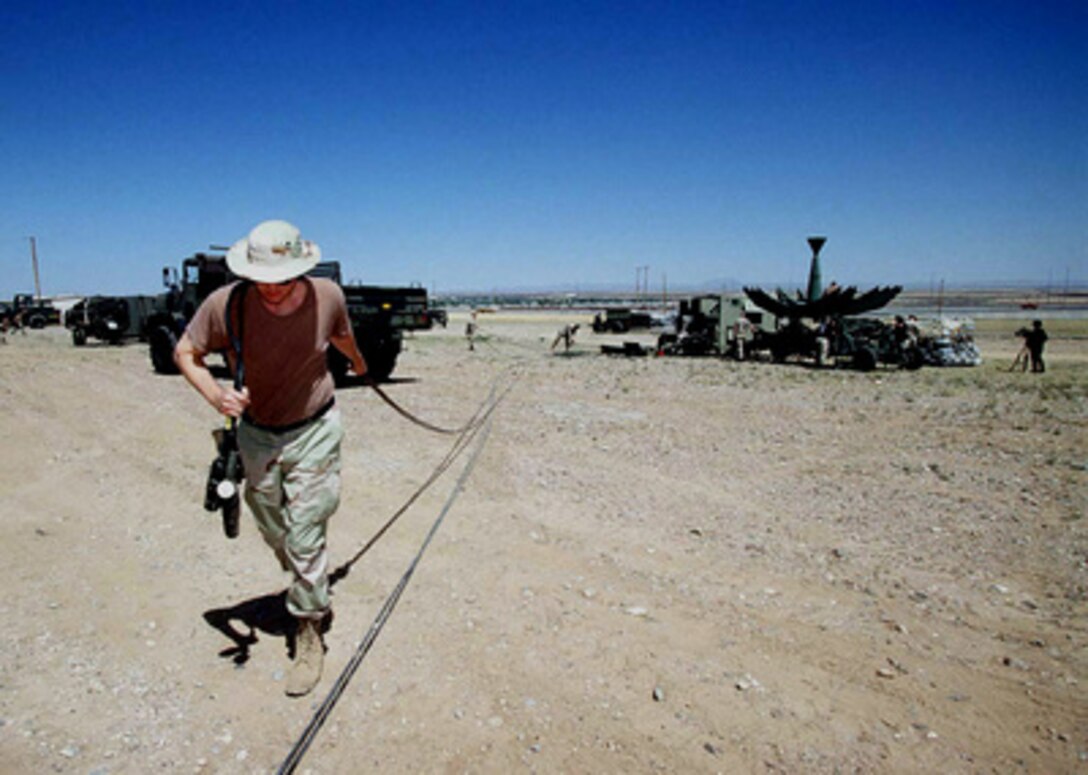 Staff Sgt. Tray Knight drags a power cable from a Ground Mobile Forces Satellite Terminal to a power generator as members of the 225th Combat Communications Squadron set up for Exercise Roving Sands 97 at El Paso, Texas, on April 8, 1997. More than 20,000 service members from all branches of the armed forces of the U.S., Canada, Germany, and the Netherlands are participating in Exercise Roving Sands 97. The exercise is designed to refine their skills in operations using an integrated air defense network of ground, missile and radar early warning systems combined with tactical fighter and bomber aircraft operating in a simulated high-threat environment. The 225th, deployed from Martin Air National Guard Station, Gadsden, Ala., will provide communications links for Roving Sands 97. 