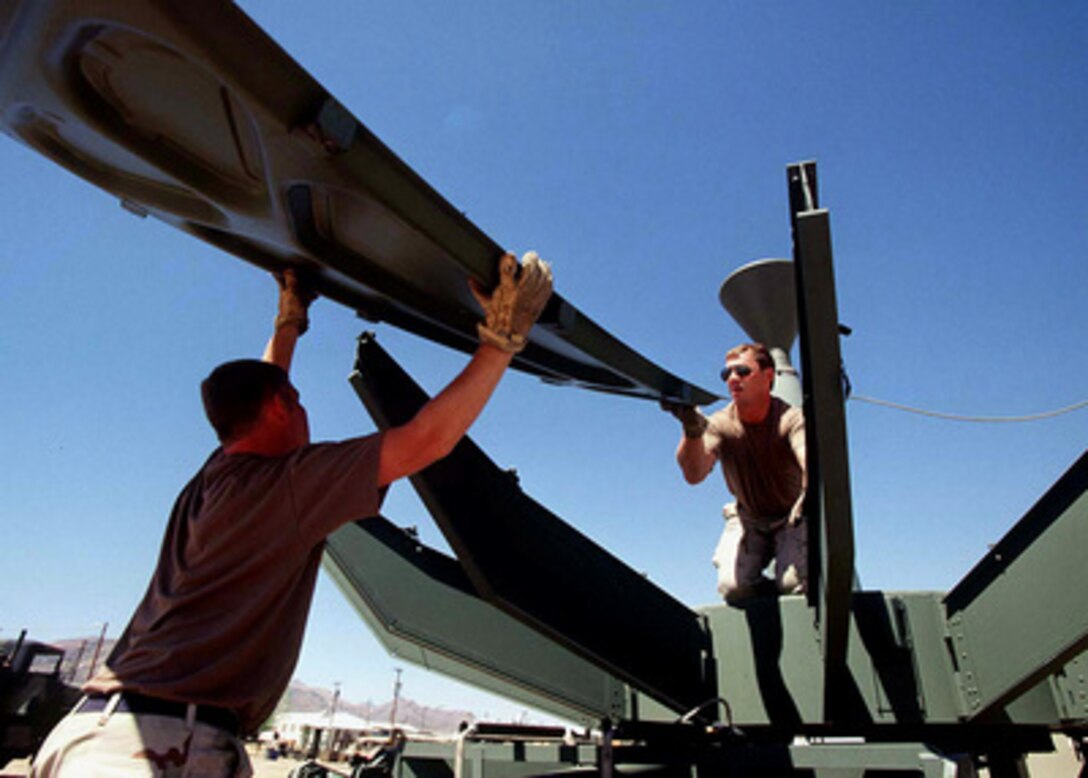 Senior Airman Joseph Roberson kneels on the center portion of a Ground Mobile Forces Satellite Terminal to receive a section of the reflector as members of the 225th Combat Communications Squadron set up for Exercise Roving Sands 97 at El Paso, Texas, on April 8, 1997. More than 20,000 service members from all branches of the armed forces of the U.S., Canada, Germany, and the Netherlands are participating in Exercise Roving Sands 97. The exercise is designed to refine their skills in operations using an integrated air defense network of ground, missile and radar early warning systems combined with tactical fighter and bomber aircraft operating in a simulated high-threat environment. The 225th, deployed from Martin Air National Guard Station, Gadsden, Ala., will provide communications links for Roving Sands 97. 