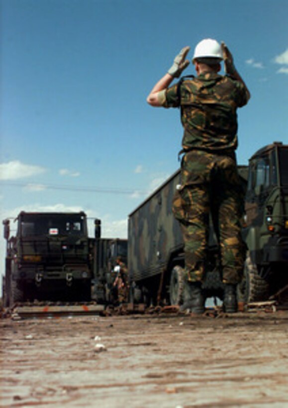 Cpl. J. van der Zouw signals a truck forward during a train unloading at Roswell, N.M. on April 10, 1997. The train is carrying vehicles which will be used by the Netherlands Army in Exercise Roving Sands 97. More than 20,000 service members from all branches of the armed forces of the U.S., Canada, Germany, and the Netherlands are participating in Exercise Roving Sands 97. The exercise is designed to refine their skills in operations using an integrated air defense network of ground, missile and radar early warning systems combined with tactical fighter and bomber aircraft operating in a simulated high-threat environment. Cpl. van der Zouw is a member of the Netherlands Army. 