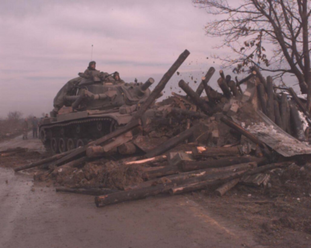 A U.S. Army combat engineer vehicle demolishes a Bosnian Serb bunker on Route Arizona near Dubrave, Bosnia and Herzegovina on Jan. 10, 1996. Route Arizona is the main deployment route from the Sava River Bridge for the NATO Implementation Force (IFOR) deployment into Bosnia and Herzegovina for Operation Joint Endeavor. The combat engineer vehicle is from the 16th Engineer Battalion, 130th Brigade, of Bamberg, Germany. 