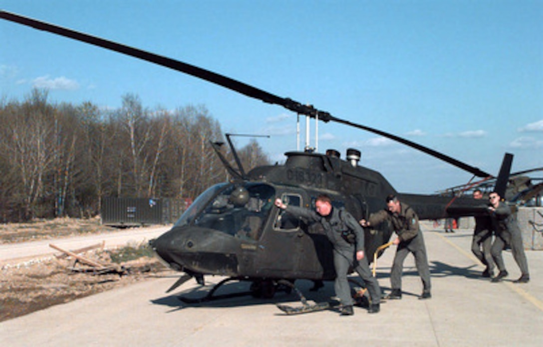 Chief Warrant Officer Chris Elam (left) gets help pushing his OH-58 Kiowa helicopter back into the hangar at the Tuzla Main airfield after a mission over Bosnia and Herzegovina on April 18, 1997. Elam is deployed as part of the Stabilization Force in Operation Joint Guard from the 2-1 Aviation Battalion, Schweinfurt, Germany. 