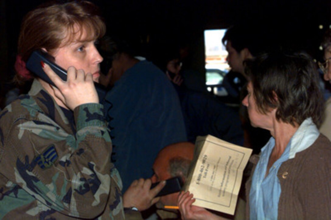 Senior Airman Lynn Cruise, of the 319th Communications Squadron, helps a flood victim make a telephone call from a hangar at Grand Forks Air Force Base, N.D. on April 21, 1997. The hangars are being used as temporary shelter for thousands of Grand Forks residents who were displaced by the flood waters of the Red River. 