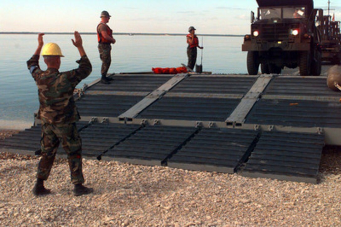 A sailor from Beachmaster Unit 2 guides the driver of a dump truck as he comes ashore near Paldiski, Estonia, from a lighter craft bringing equipment from the S.S. Sgt. Matej Kocak during Exercise Baltic Challenge 97, on July 14, 1997. Baltic Challenge '97 is a multinational exercise conducted as a NATO Partnership for Peace initiative involving more than 2,600 military personnel from Denmark, Estonia, Finland, Latvia, Lithuania, Norway, Sweden, and the U.S. The focus of the training is peacekeeping tasks and humanitarian assistance operations. The lighter craft are being used to move equipment off-loaded from the Maritime Prepositioning Ships anchored off shore to the exercise area on the beach. Beachmaster Unit 2 is homeported in Little Creek, Va. 