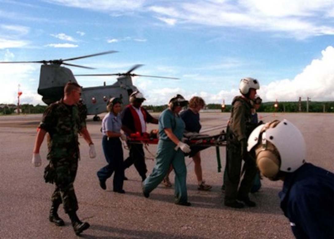 A survivor of the Korean Airline crash is moved from an evacuation helicopter to the U. S. Naval Hospital by Navy medical personnel, flight crew, and civilian volunteers on Aug 6, 1997.   U.S. Navy, U.S. Coast Guard, U.S. Air Force, and numerous civilian rescue teams, currently assisting in the search and rescue efforts of KAL flight 801, evacuated survivors from the crash site during the early morning of August 6th. 