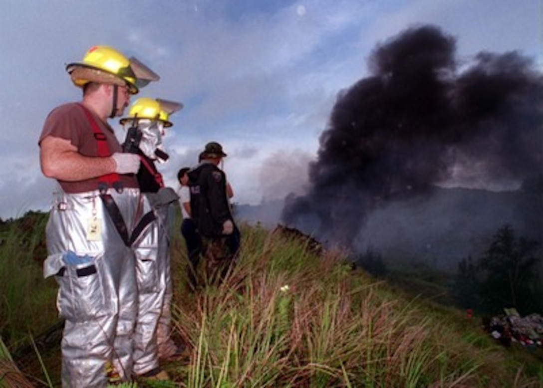 U.S. Air Force firefighters and Guam Police Department rescuers survey the wreckage of Korean Airlines flight 801 on Aug 6, 1997.   U.S. Navy, U.S. Coast Guard, U.S. Air Force, and numerous civilian rescue teams, currently assisting in the search and rescue efforts of KAL flight 801, evacuated survivors from the crash site during the early morning of August 6th. 