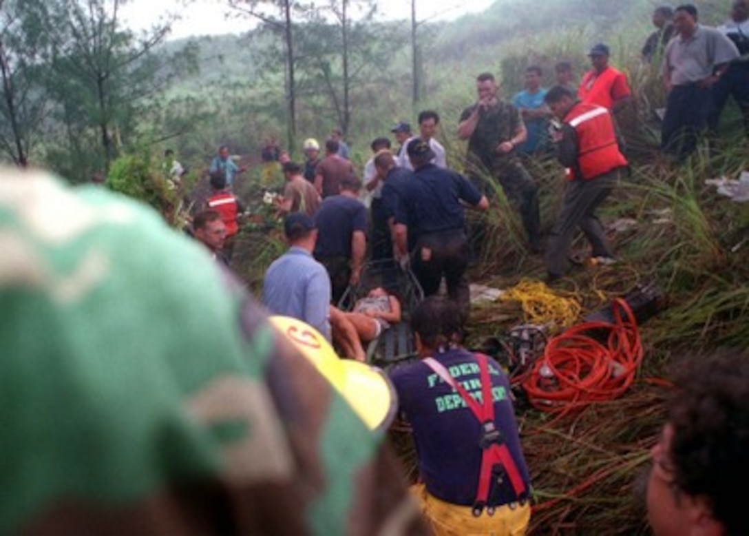 U.S. Coast Guard, U.S. Navy and U.S. Air Force rescuers assist Guam firefighters in evacuating a young survivor of Korean Airlines flight 801 on Aug 6, 1997.   U.S. Navy, U.S. Coast Guard, U.S. Air Force, and numerous civilian rescue teams, currently assisting in the search and rescue efforts of KAL flight 801, evacuated survivors from the crash site during the early morning of August 6th. 