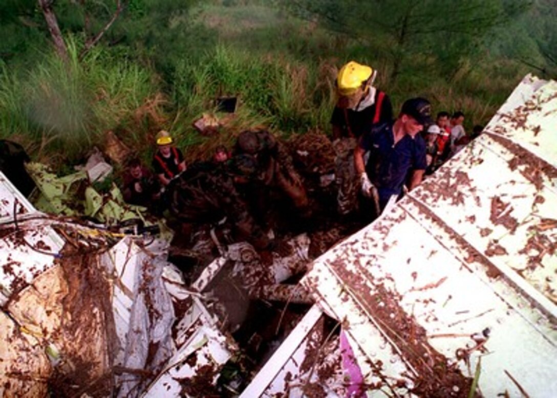 U. S. Navy Explosive Ordnance Disposal personnel, along with Coast Guard and Air Force rescuers, search wreckage for survivors on Aug. 6, 1997.  U.S. Navy, U.S. Coast Guard, U.S. Air Force, and numerous civilian rescue teams, currently assisting in the search and rescue efforts of KAL flight 801, evacuated survivors from the crash site during the early morning of August 6th. 