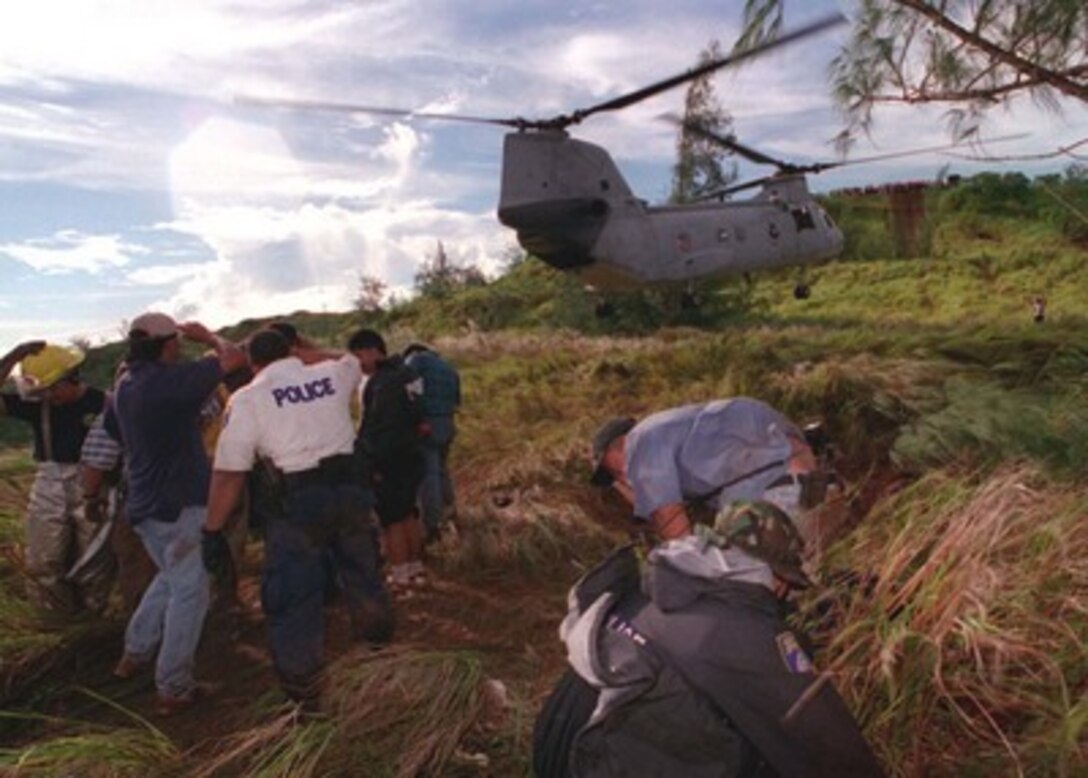 Guam Police Department personnel take cover as a U.S. Navy CH-46 Sea Knight helicopter from Helicopter Combat Support Squadron 5 evacuates survivors to U. S. Naval Hospital, Guam, on Aug 6, 1997.  U.S. Navy, U.S. Coast Guard, U.S. Air Force, and numerous civilian rescue teams, currently assisting in the search and rescue efforts of KAL flight 801, evacuated survivors from the crash site during the early morning of August 6th. 