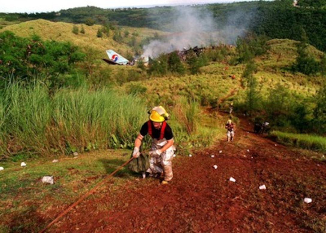 Fire fighters use an ascent line to pull themselves up the steep slope from the crash site of Korean Airlines flight 801 on Aug. 6, 1997.  U.S. Navy, U.S. Coast Guard, U.S. Air Force, and numerous civilian rescue teams, currently assisting in the search and rescue efforts of KAL flight 801, evacuated survivors from the crash site during the early morning of August 6th. 